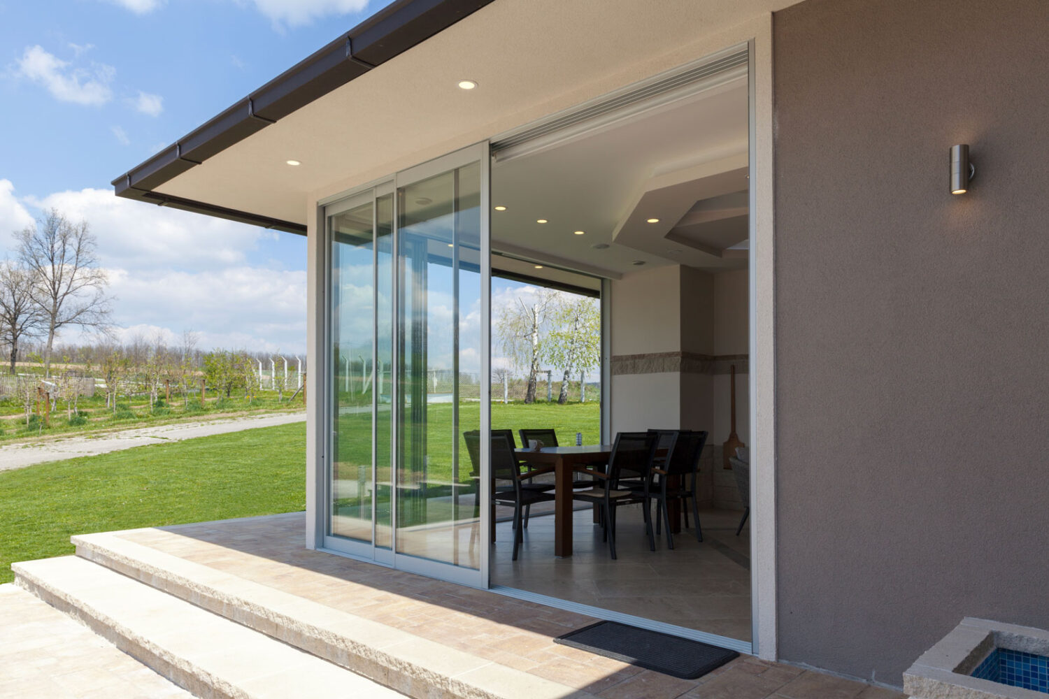 Veranda moderna con porte-finestre in vetro che danno su un giardino